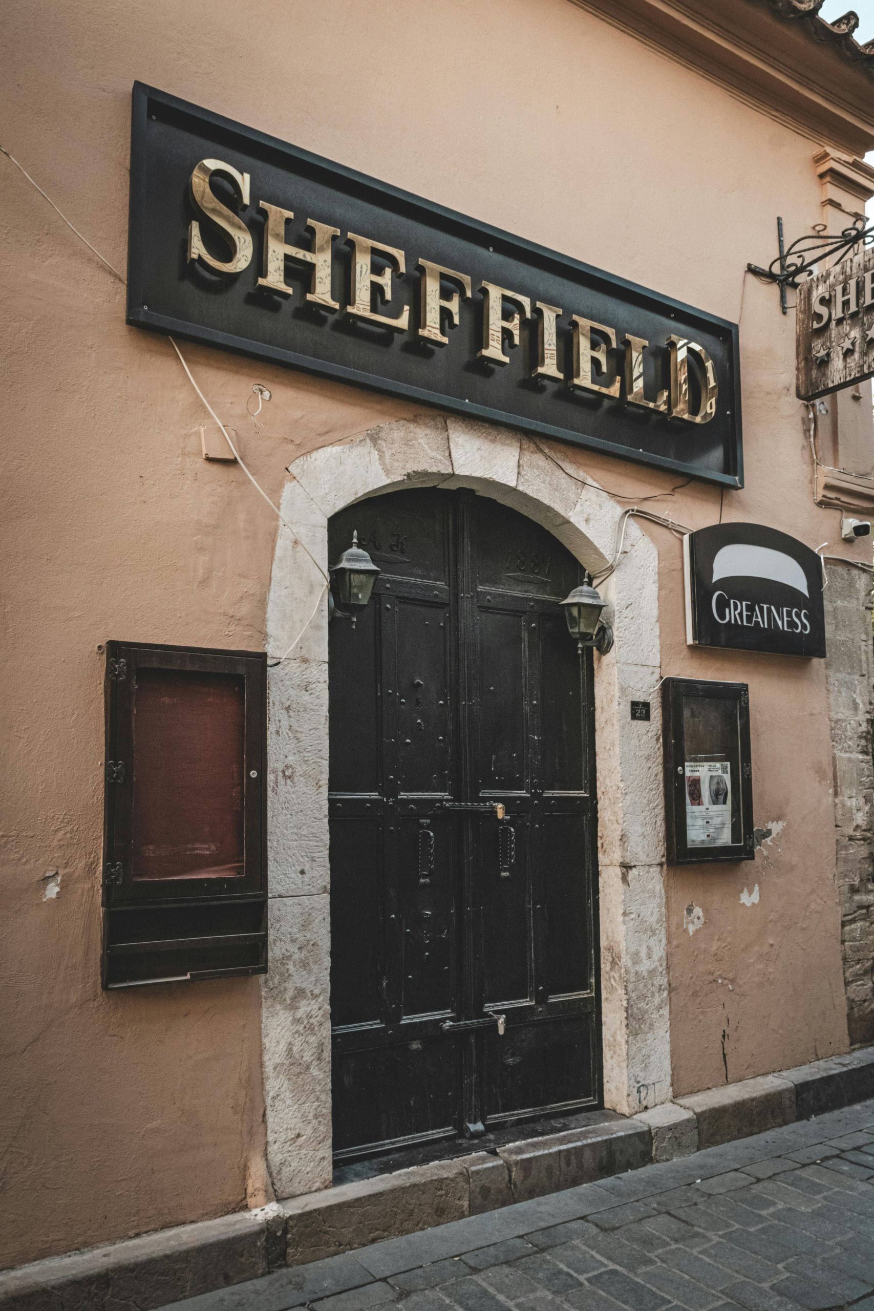 An urban entrance with a vintage Sheffield sign above a rustic wooden door.