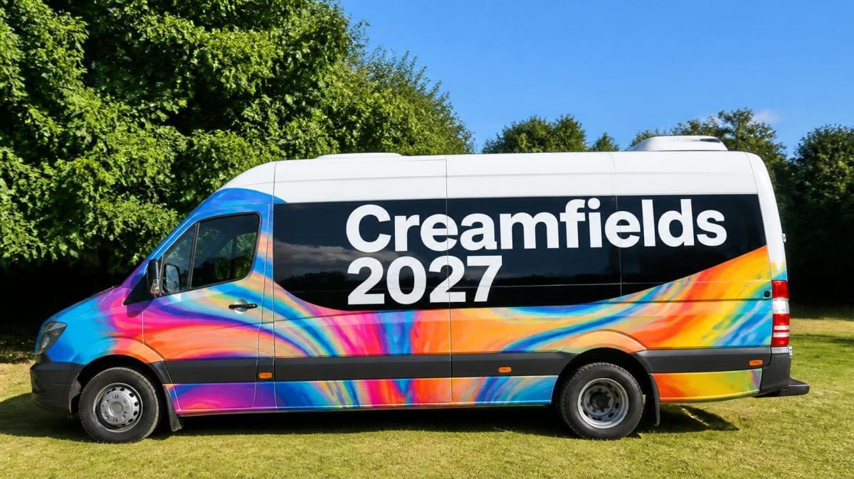 Creamfields 2027 transport minibus with rainbow wrap parked on grass