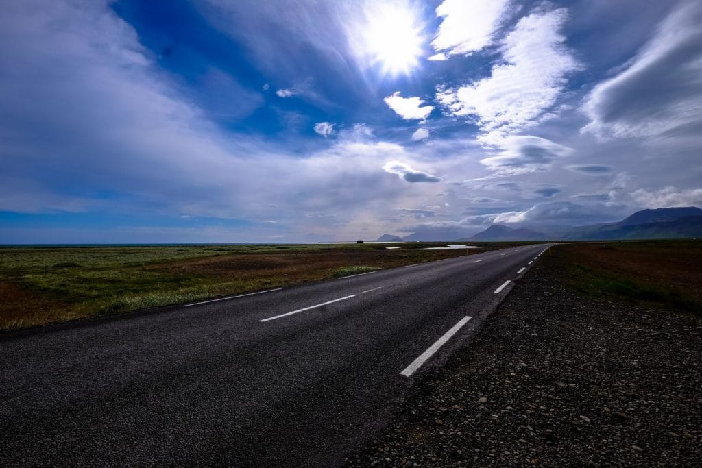 Empty UK motorway stretching into the distance under a blue sky, representing long-distance minibus transport